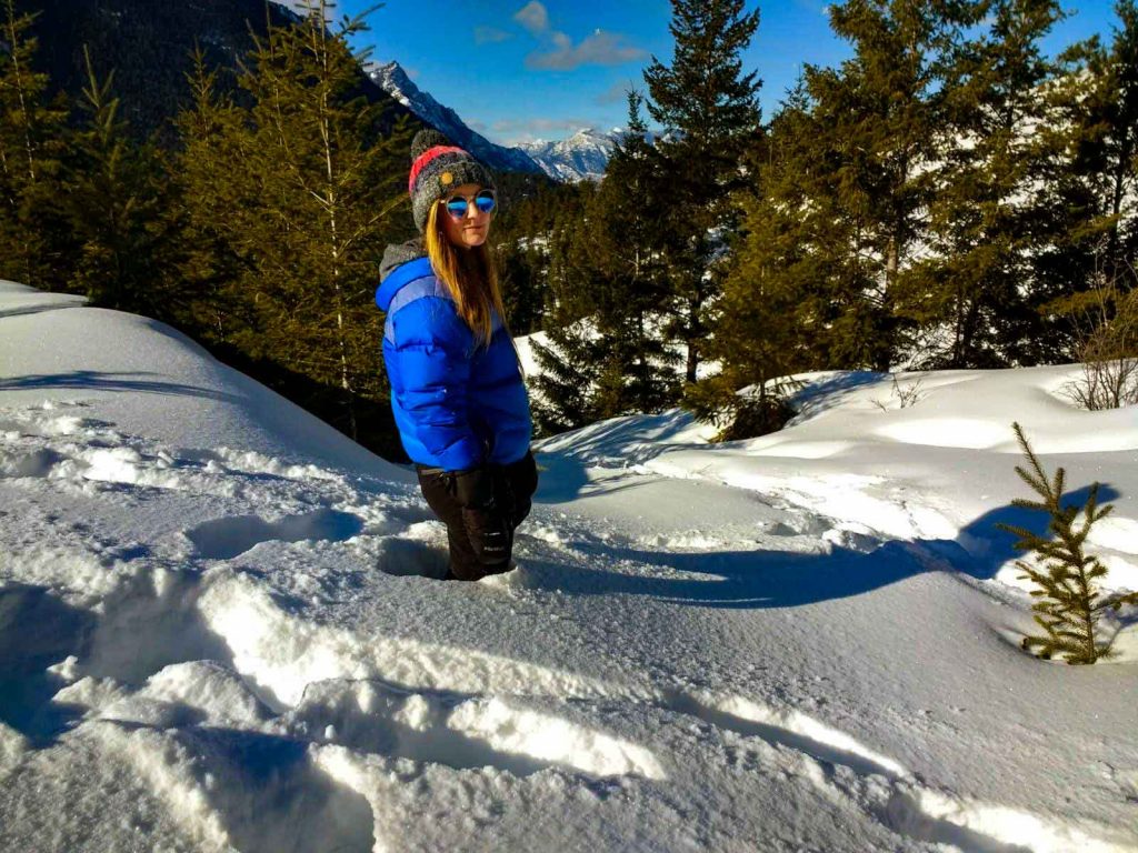 Woman in blue coat and bobble hat stands in deep snow