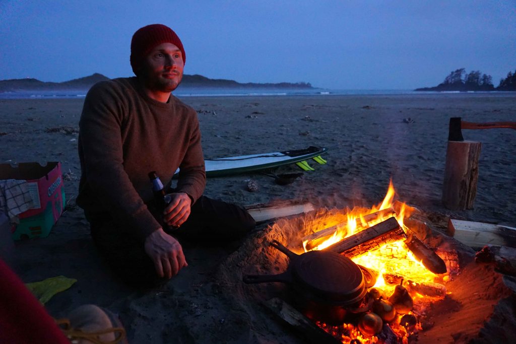 Man cooks using a beach fire