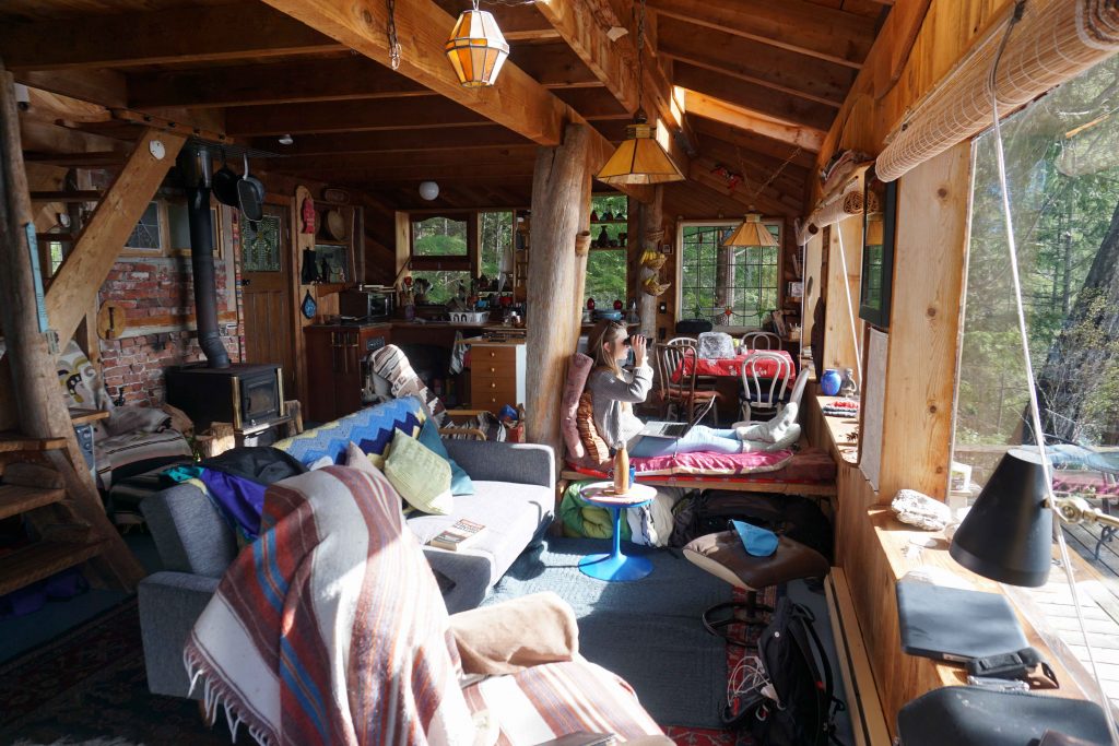 Woman looks through binocular while sitting in wood cabin