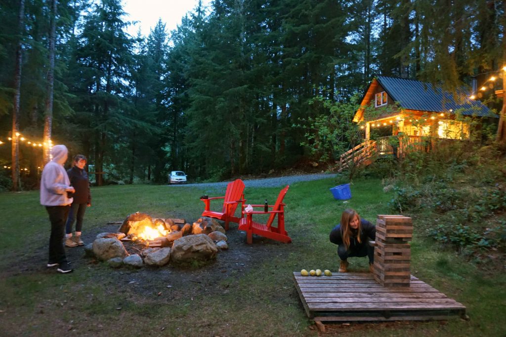 Three people playing Jenga near a campfire