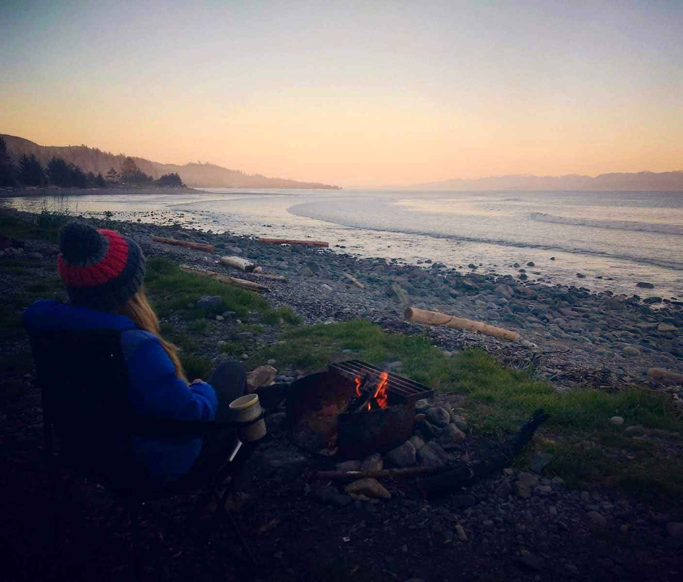 Woman sits in from of beach fire