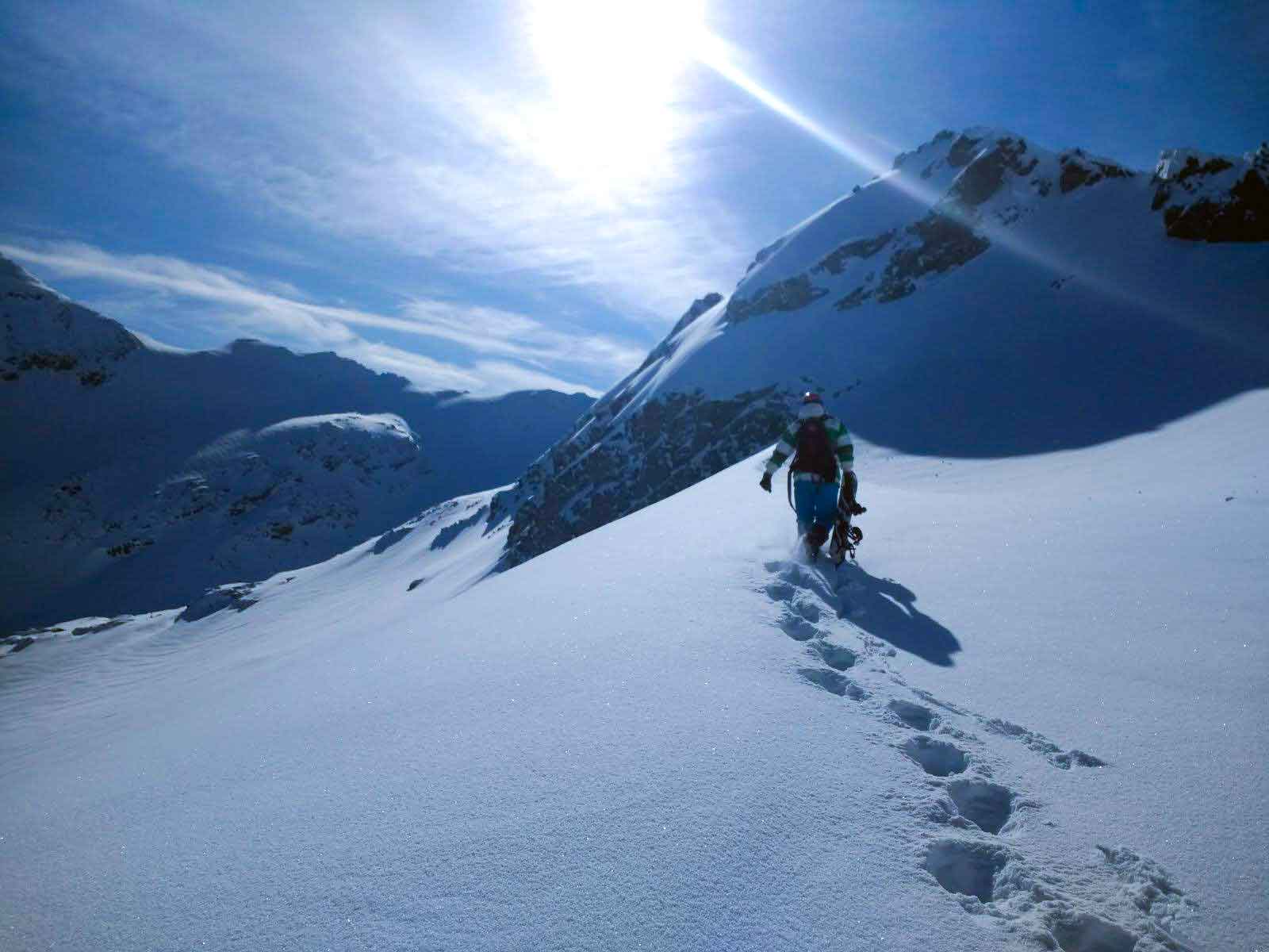 Man walks with snowboard along mountain ridge
