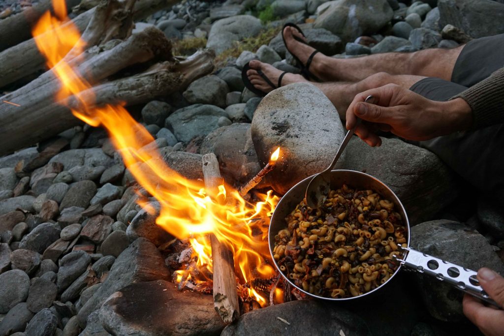 Bowl of food cooks over a campfire