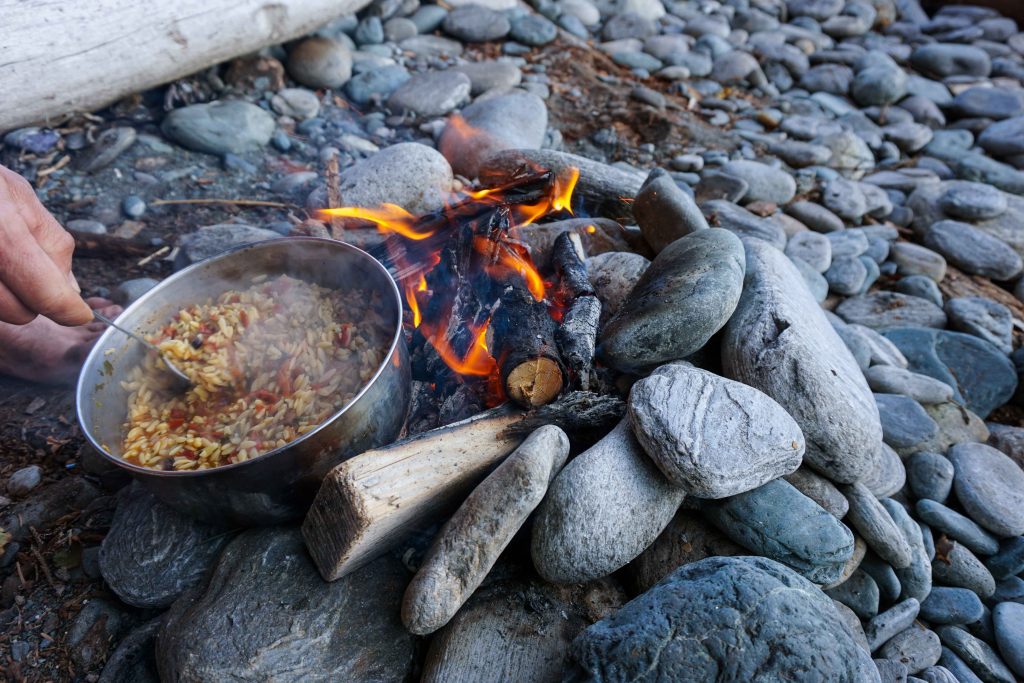 Bowl of food cooks over a campfire