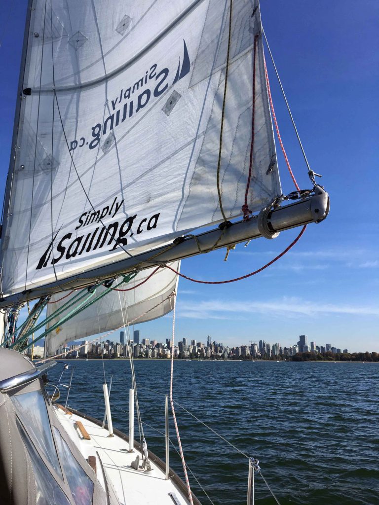 Sail boat on the sea with city in the distance