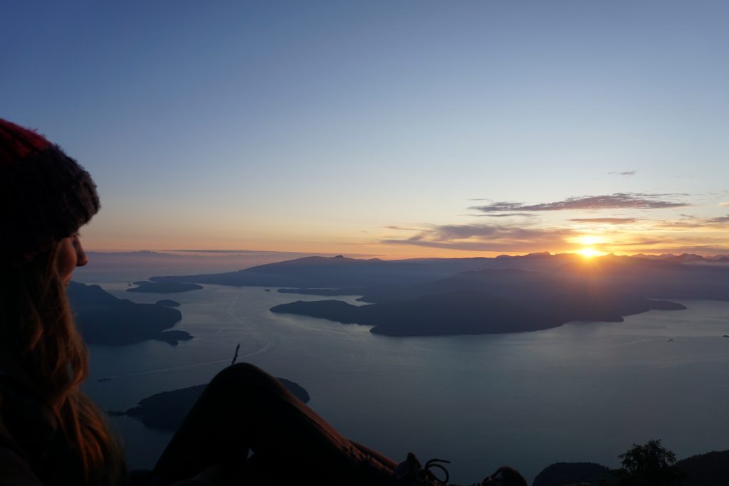 Woman watches sun set over sea and islands