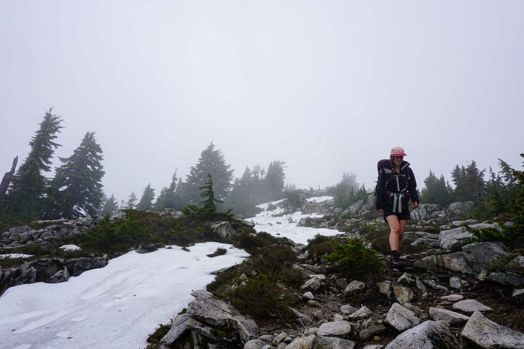 Woman walks along snowy rocky ridge