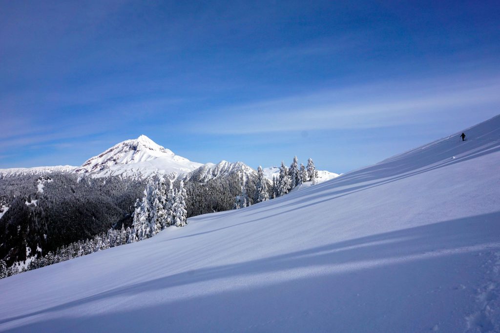 backcountry ski tourer in the distance surrounding by snowy slopes