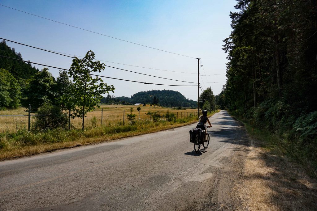 Woman rides bike loaded with panniers along road