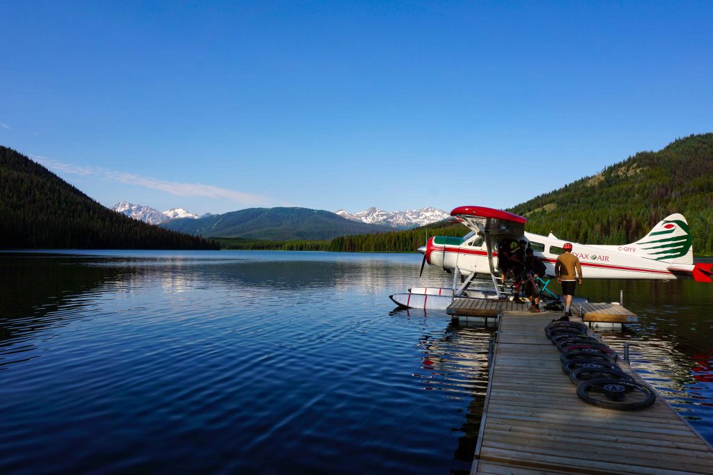 Floatplane on alpine lake with mountain bike wheels loaded onto the wooden wharf