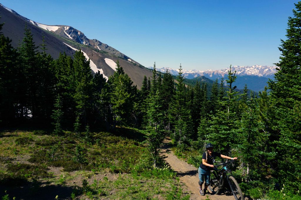 Woman pushes bike up mountain trail