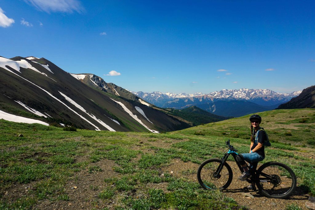 Woman sits on mountain bike on mountain pass