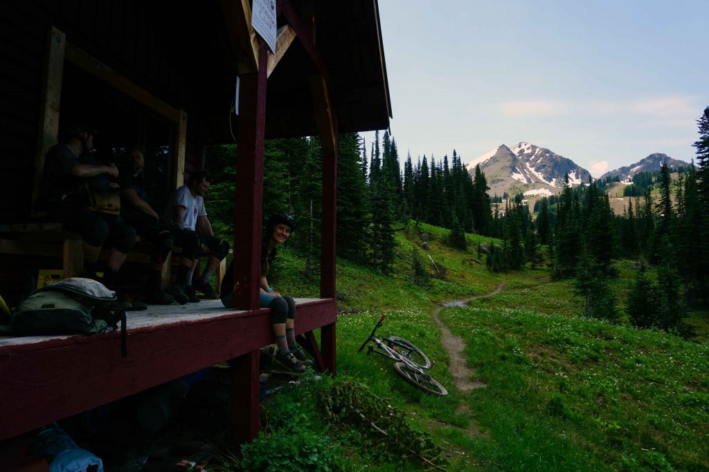People sit on deck of wooden backcountry cabin