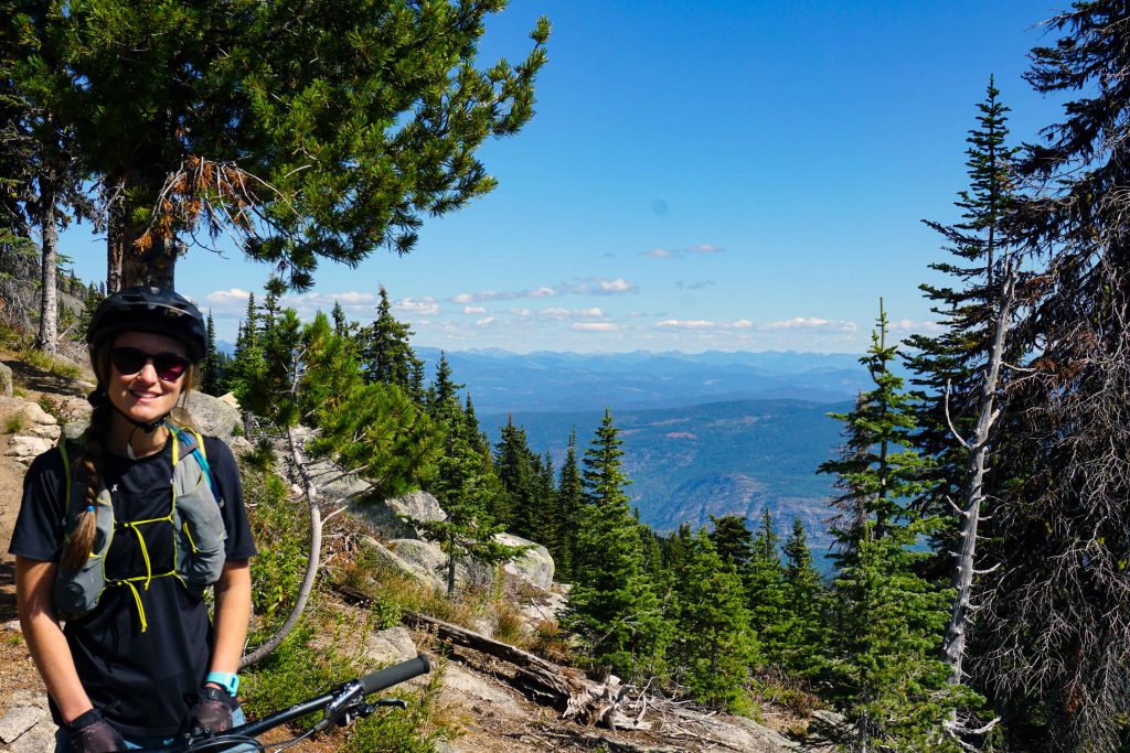 Woman on mountain bike smiles at the camera.